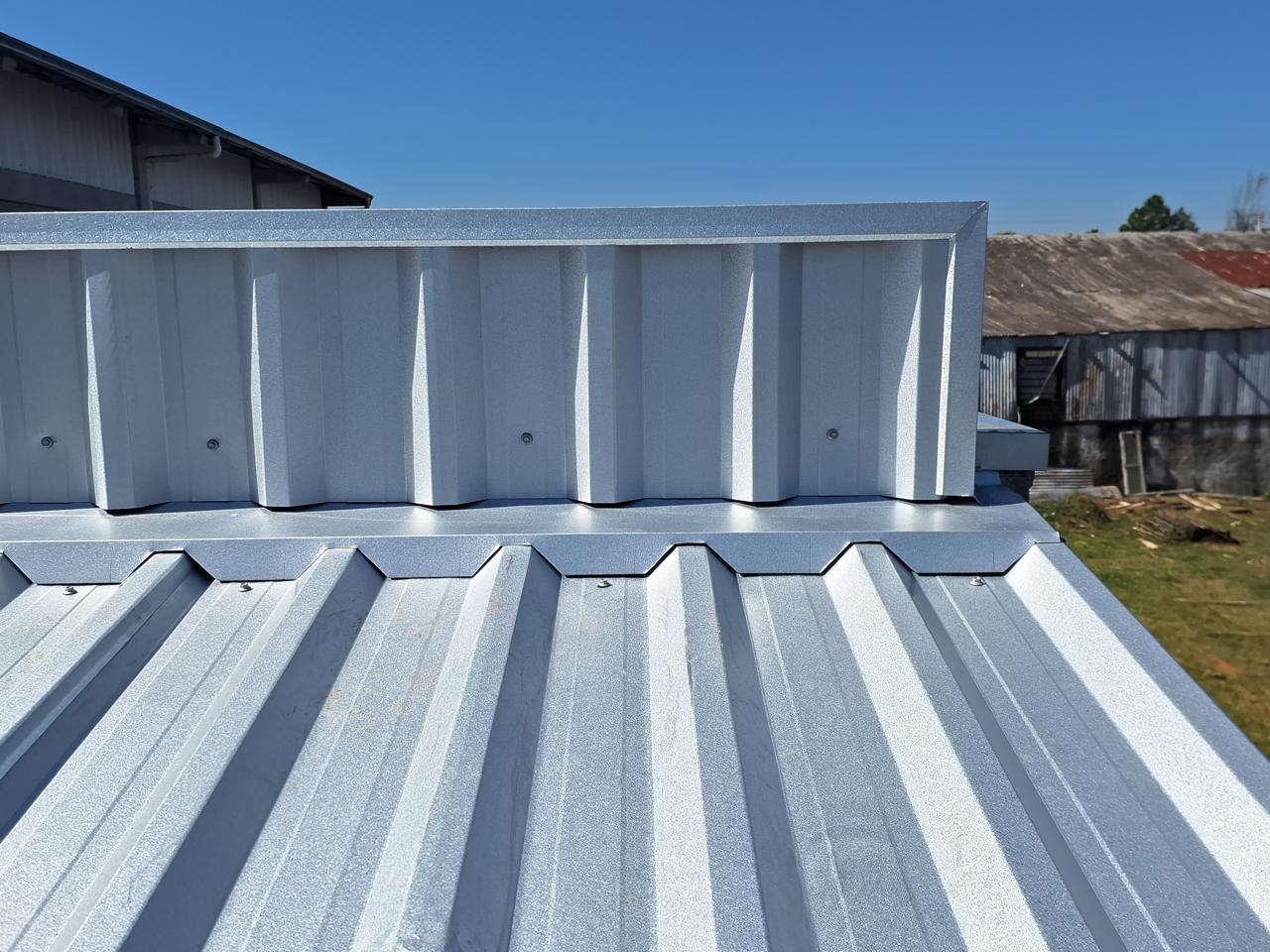 Calha metálica instalada em telhado com telhas claras